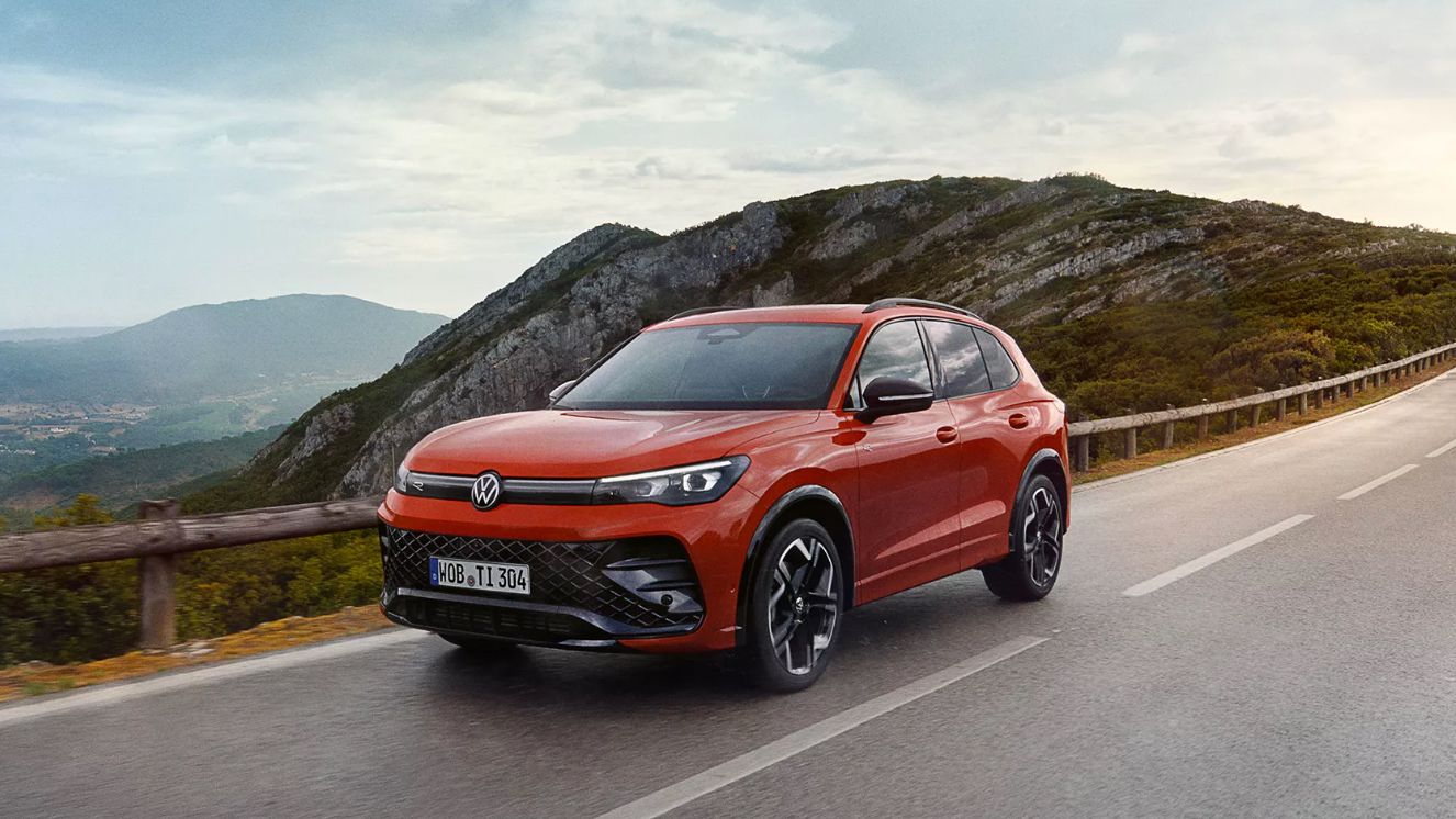 VW Der neue Tiguan Roter VW Tiguan fährt eine Straße entlang.
