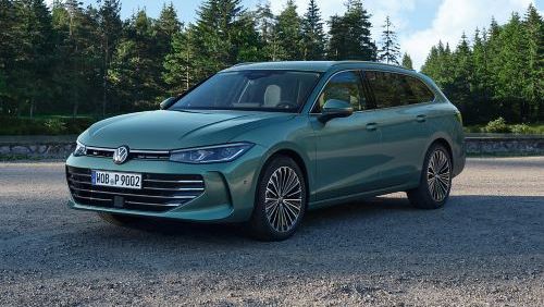 VW Passat in blaugrün steht auf einer Kiesfläche, das Gelände grenzt an einen Tannenwald.